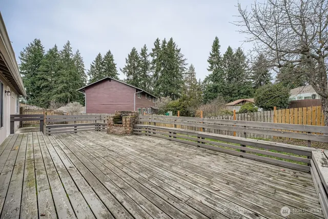 a view of house with deck outdoor seating and trees in the background