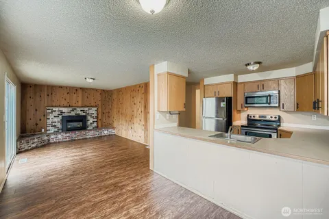 a large kitchen with a stove a refrigerator and a view of living room