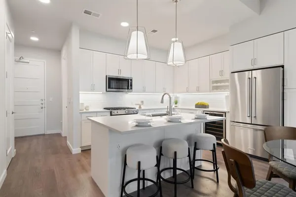 a kitchen with stainless steel appliances granite countertop a sink a stove a refrigerator cabinets a dining table and chairs