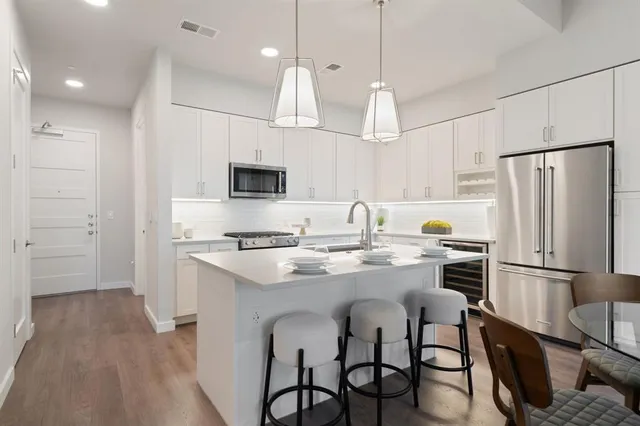 a kitchen with stainless steel appliances granite countertop a sink a stove a refrigerator cabinets a dining table and chairs