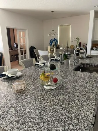 a kitchen with granite countertop a sink and living room