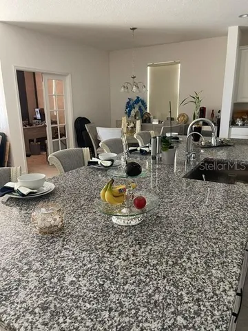 a kitchen with granite countertop a sink and living room