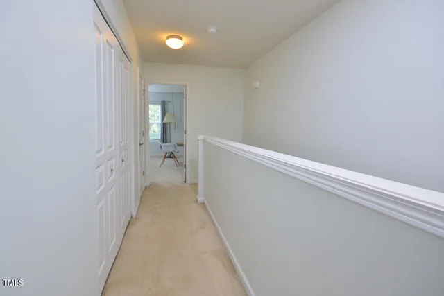 a view of a hallway with wooden floor and a bathroom