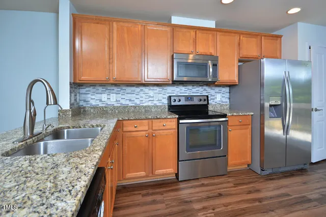 a kitchen with granite countertop a sink stainless steel appliances and counter space