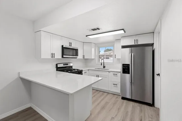 a kitchen with white cabinets and stainless steel appliances