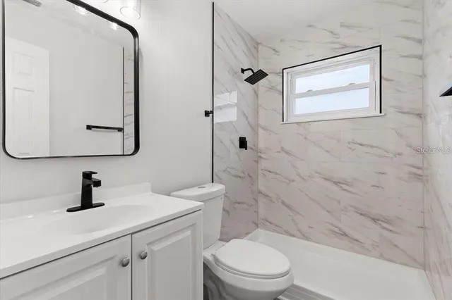 a bathroom with a toilet a sink a mirror a vanity and window