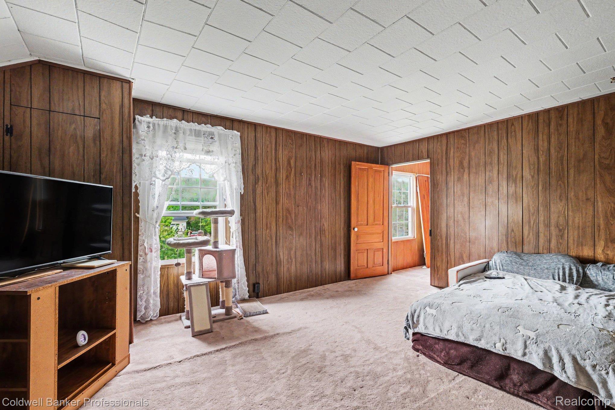 3105 East Dodge Road Clio, MI 48420 - Photo 13 of 28 Bedroom-2nd Floor featuring light carpet, window, wooden walls leads to back staircase.