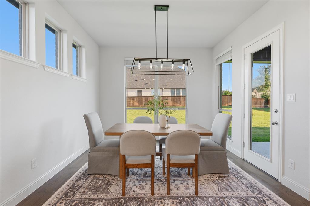 1316 Limestone Ridge Road Mansfield, TX 76063 - Photo 14 of 40 Bright dining area featuring a modern linear chandelier, wood-finish flooring, and multiple windows
