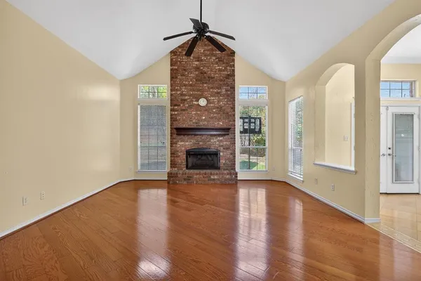 a view of an empty room with wooden floor fireplace and a window