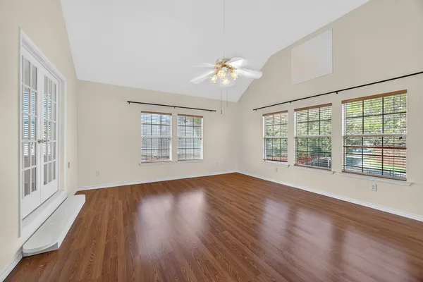 a view of an empty room with wooden floor and a window