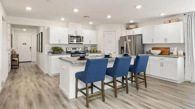 a kitchen with stainless steel appliances a dining table chairs refrigerator and microwave