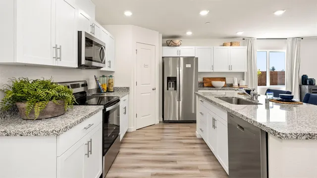 a kitchen with stainless steel appliances granite countertop a sink a stove and a refrigerator