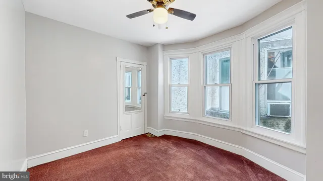 an empty room with windows and ceiling fan