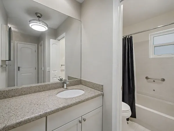 a bathroom with a granite countertop sink a mirror and a bathtub