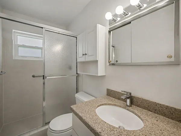 a bathroom with a granite countertop sink toilet a mirror and shower