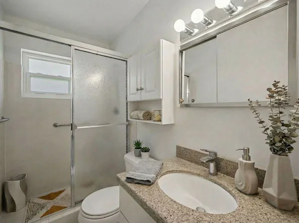 a bathroom with a granite countertop sink a toilet and mirror