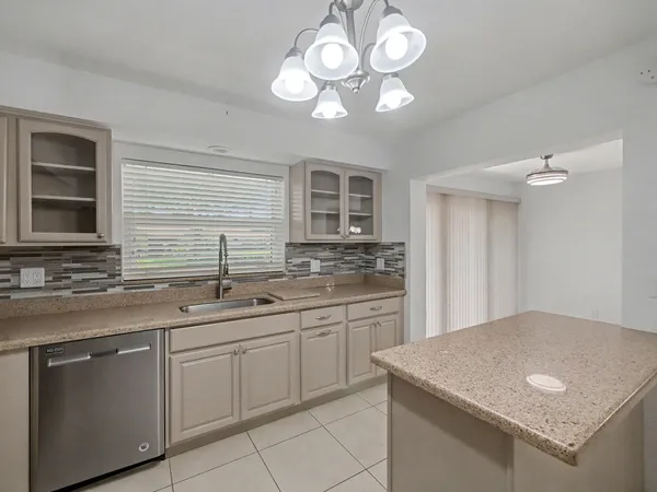 a kitchen with stainless steel appliances granite countertop a sink dishwasher a stove and a refrigerator with wooden floor