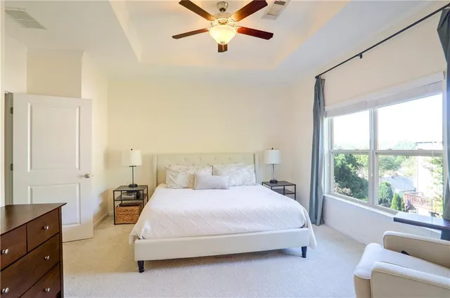 a bedroom with a large bed and a chandelier fan