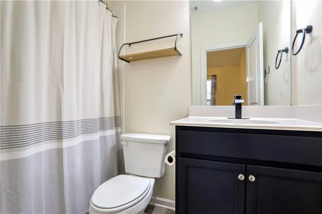 a bathroom with a sink a toilet a mirror and shower curtain
