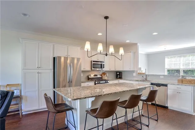 a kitchen with stainless steel appliances granite countertop a kitchen island a stove a table and chairs