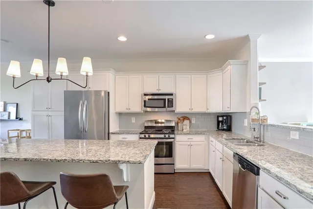 a kitchen with granite countertop a sink a counter top space appliances and cabinets