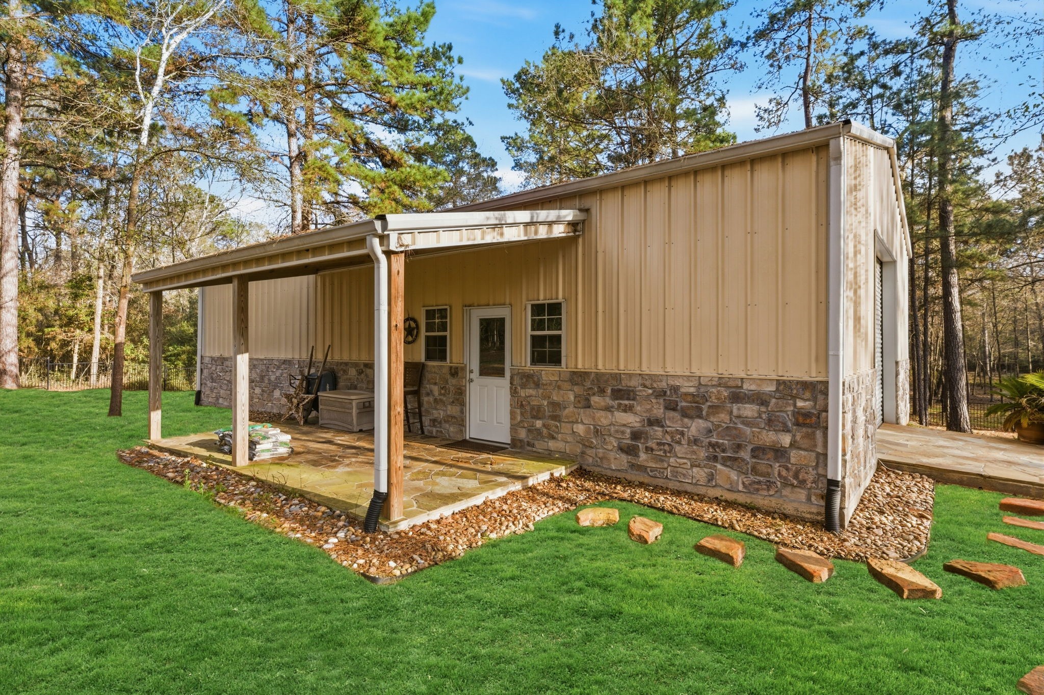 280 Sundog Road Huntsville, TX 77340 - Photo 48 of 50 1,500 sq ft metal building with covered porch, attractive stone accents, entry door, and large overhead door—ideal for vehicles, equipment, or larger projects.