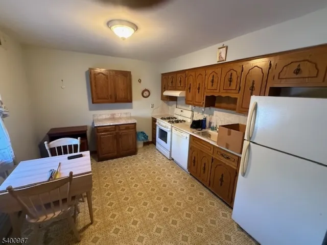 a kitchen with a refrigerator a stove top oven a sink dishwasher and wooden cabinets