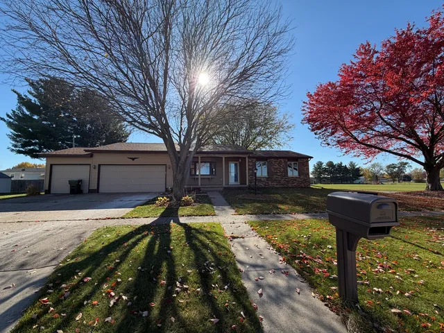 a front view of a house with a yard large tree and a wooden bench