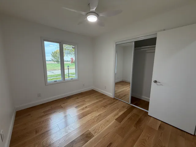 an empty room with wooden floor cabinet and windows