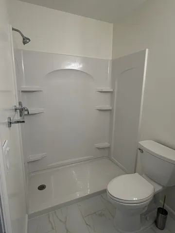 a white toilet sitting next to a shower
