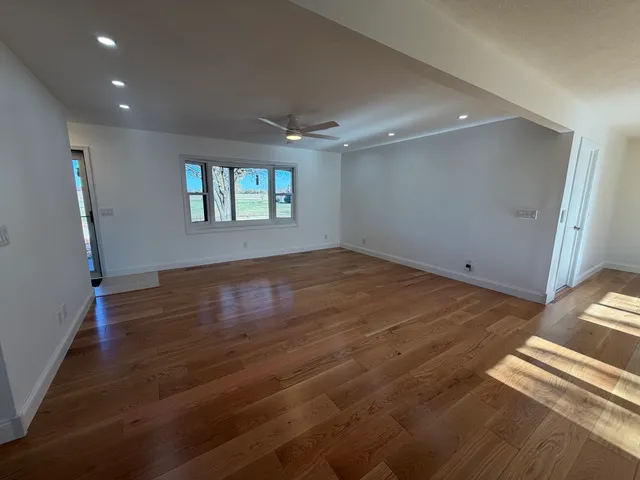 an empty room with wooden floor and windows