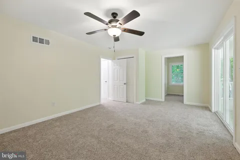 a view of an empty room with a ceiling fan and window