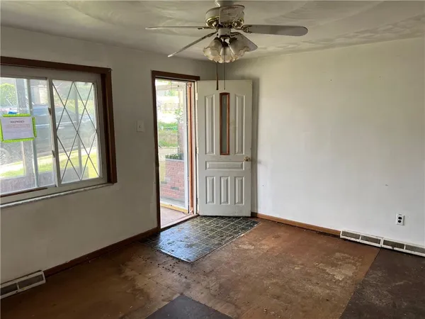 an empty room with chandelier fan and windows