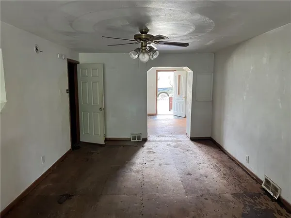 an empty room that has a chandelier fan and a window