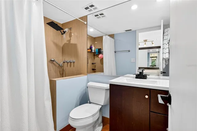 a bathroom with a sink a toilet a mirror and shower