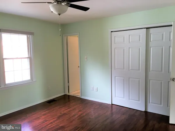 an empty room with wooden floor fan and windows