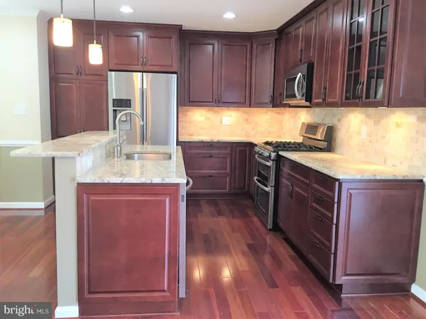 a kitchen with stainless steel appliances granite countertop wooden cabinets a stove top oven a sink and dishwasher with wooden floor