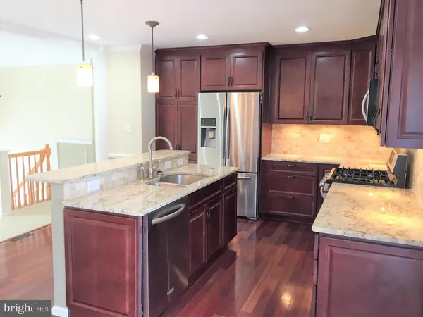 a kitchen with kitchen island granite countertop lots of counter top space and refrigerator