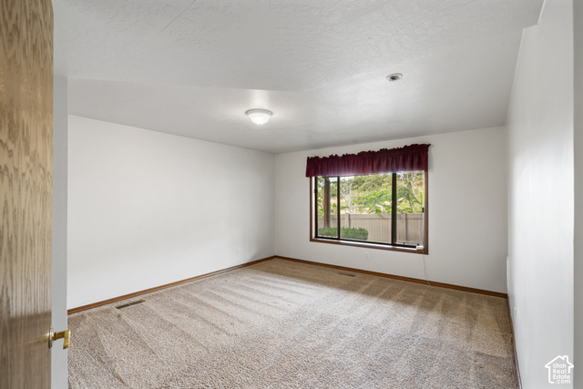 1373 Pheasant Ridge Circle Bountiful, UT 84010 - Photo 40 of 50 Carpeted room with white walls, a large window, wood-finish trim, and a flush mount light fixture