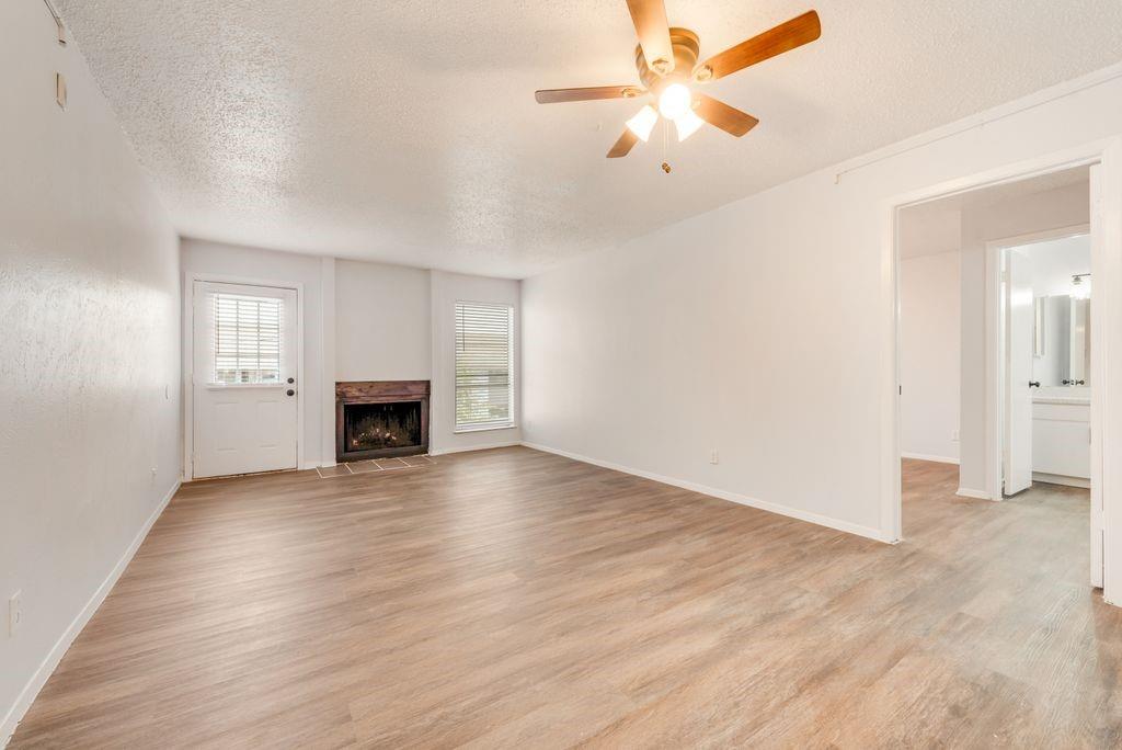 5514 Boca Raton Boulevard, Unit 438 Fort Worth, TX 76112 - Photo 3 of 25 an empty room with fan and a fireplace