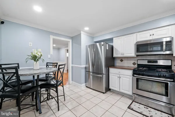 a kitchen with stainless steel appliances a stove a microwave a dining table and chairs