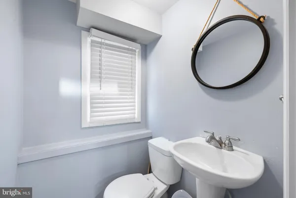 a bathroom with a toilet a sink a mirror and a window