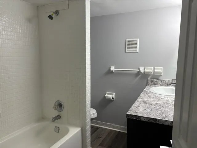 a bathroom with a granite countertop sink a toilet and bathtub