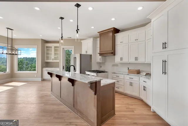 a large kitchen with stainless steel appliances kitchen island granite countertop a stove a refrigerator a sink and a dining table with wooden floor