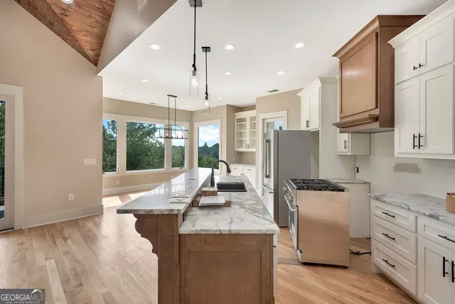 a kitchen with stainless steel appliances granite countertop a refrigerator a oven and white cabinets with wooden floors