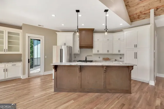 a large kitchen with stainless steel appliances granite countertop a sink cabinets and wooden floor