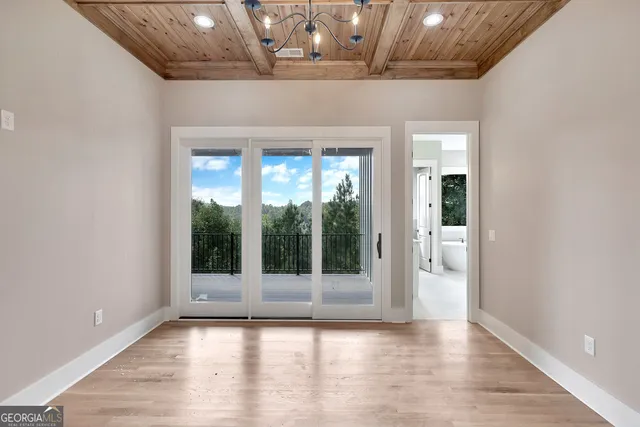 a view of an empty room with wooden floor and a glass door