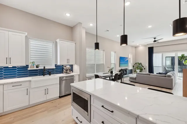 a kitchen with sink stove and white cabinets with wooden floor