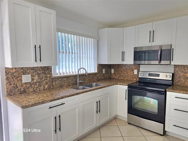 a kitchen with granite countertop a sink stove and microwave