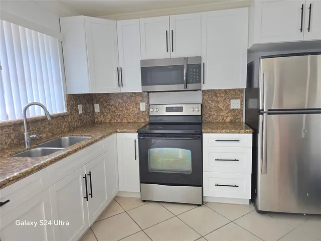 a kitchen with white cabinets sink and refrigerator
